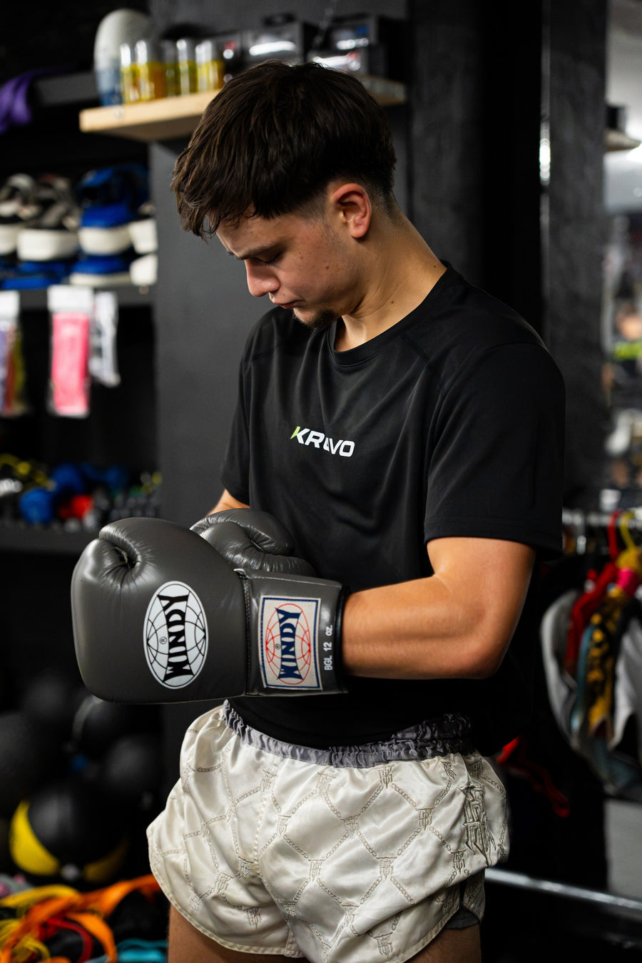 Young fighter in a KRUVO tee strapping on boxing gloves